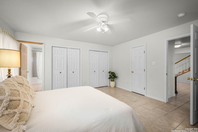 bedroom featuring ceiling fan, multiple closets, and light tile patterned flooring