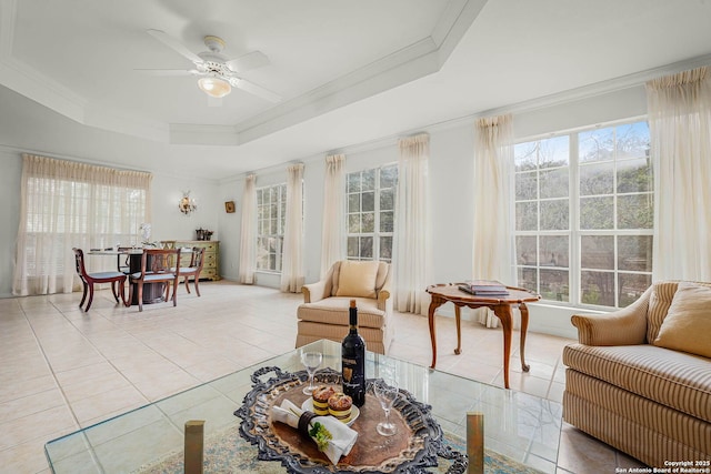 tiled living room featuring a wealth of natural light, ornamental molding, a raised ceiling, and ceiling fan