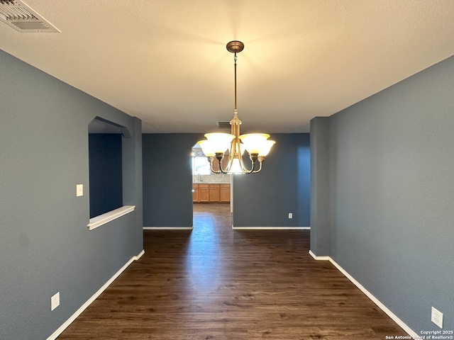 unfurnished dining area featuring dark hardwood / wood-style floors and a notable chandelier