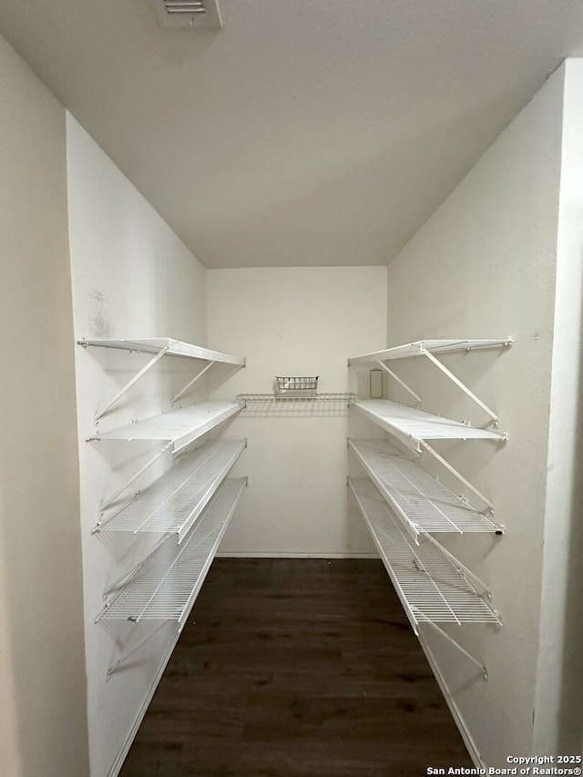 spacious closet featuring lofted ceiling and dark hardwood / wood-style floors