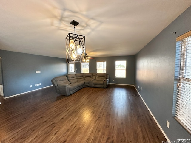 unfurnished living room with dark wood-type flooring and an inviting chandelier