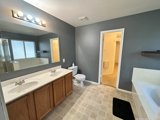 bathroom with vanity, toilet, a textured ceiling, and a tub