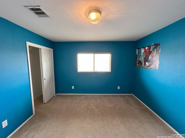 unfurnished bedroom featuring light carpet and a textured ceiling