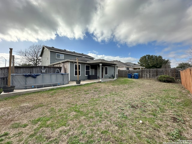 back of house featuring a fenced in pool and a lawn