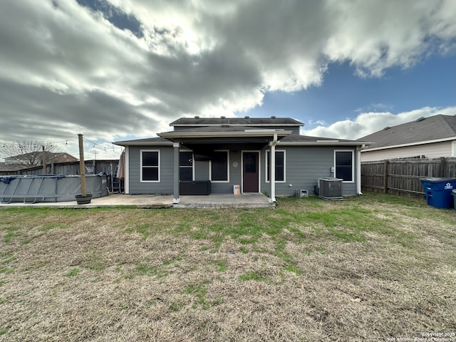 back of house with central AC unit, a yard, a covered pool, and a patio area