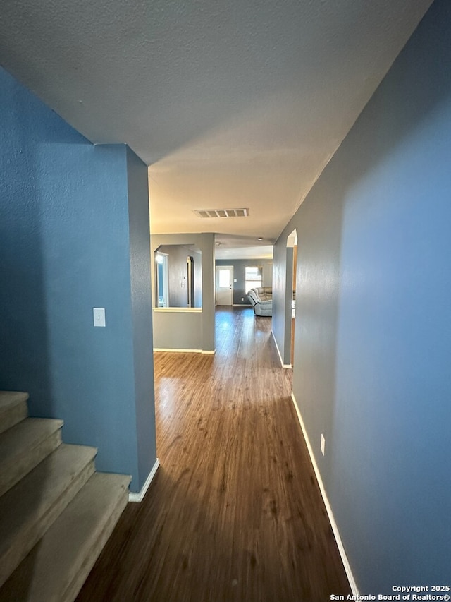 corridor with hardwood / wood-style flooring and a textured ceiling