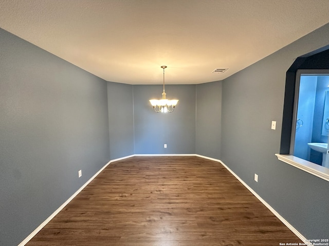 unfurnished room with a notable chandelier and wood-type flooring