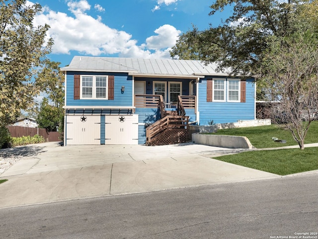 view of front of home featuring covered porch, metal roof, a front lawn, and fence