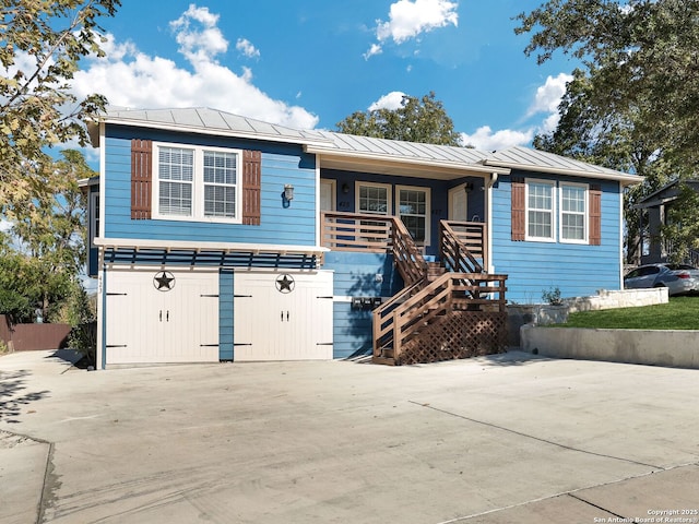 view of front of home featuring metal roof, concrete driveway, a porch, and a standing seam roof