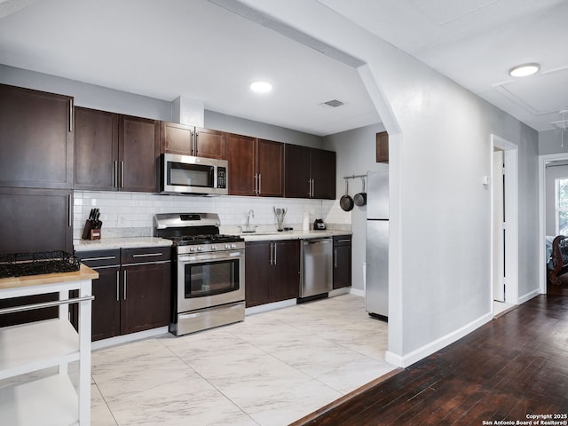 kitchen with arched walkways, tasteful backsplash, light countertops, visible vents, and appliances with stainless steel finishes