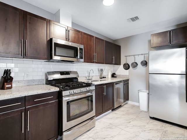 kitchen featuring visible vents, appliances with stainless steel finishes, light stone countertops, marble finish floor, and a sink