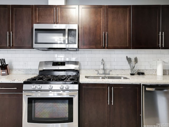 kitchen featuring light stone countertops, backsplash, stainless steel appliances, and a sink