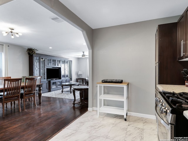 kitchen with light countertops, visible vents, open floor plan, dark brown cabinetry, and baseboards