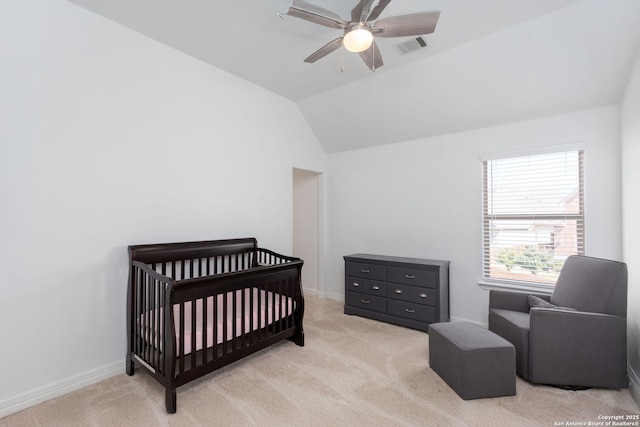 bedroom featuring vaulted ceiling, a nursery area, light colored carpet, and ceiling fan