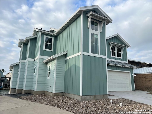 view of property exterior featuring an attached garage, a standing seam roof, driveway, and board and batten siding