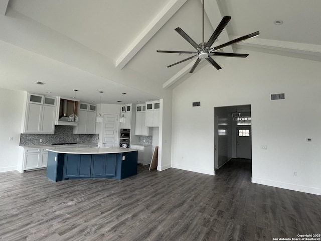 kitchen with light countertops, visible vents, open floor plan, white cabinets, and beamed ceiling