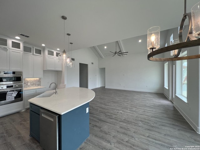 kitchen featuring stainless steel appliances, a sink, a ceiling fan, white cabinetry, and decorative backsplash