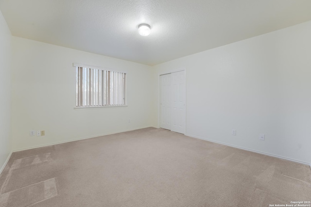 empty room with light carpet and a textured ceiling