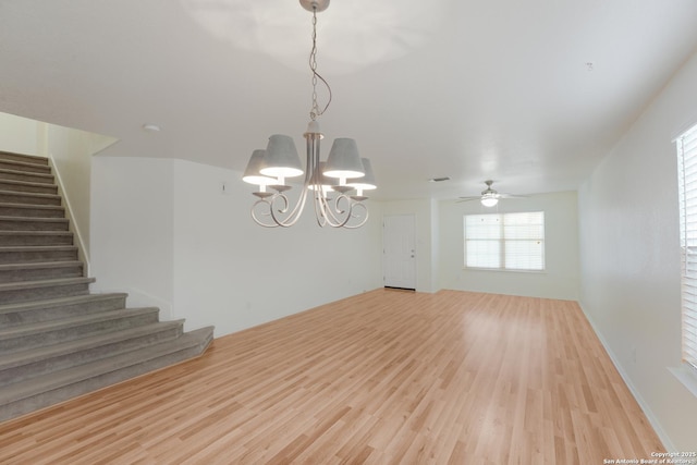 empty room featuring ceiling fan with notable chandelier and light hardwood / wood-style flooring