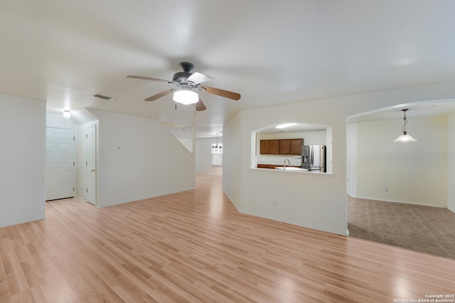 unfurnished living room featuring ceiling fan, sink, and light hardwood / wood-style floors