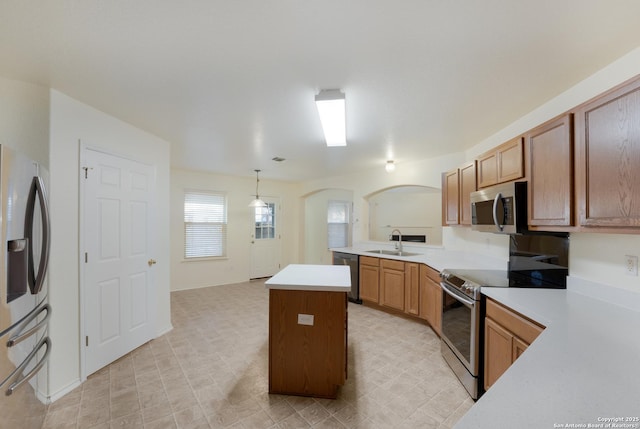 kitchen featuring sink, hanging light fixtures, appliances with stainless steel finishes, kitchen peninsula, and a kitchen island