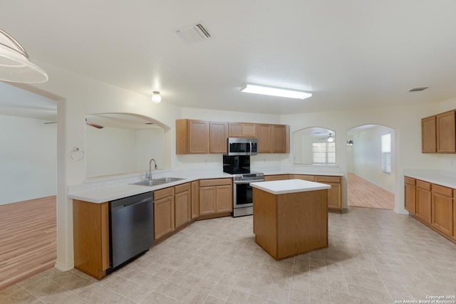 kitchen featuring sink, appliances with stainless steel finishes, kitchen peninsula, a kitchen island, and ceiling fan