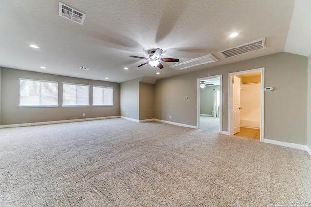 spare room featuring vaulted ceiling, light colored carpet, ceiling fan, and a textured ceiling