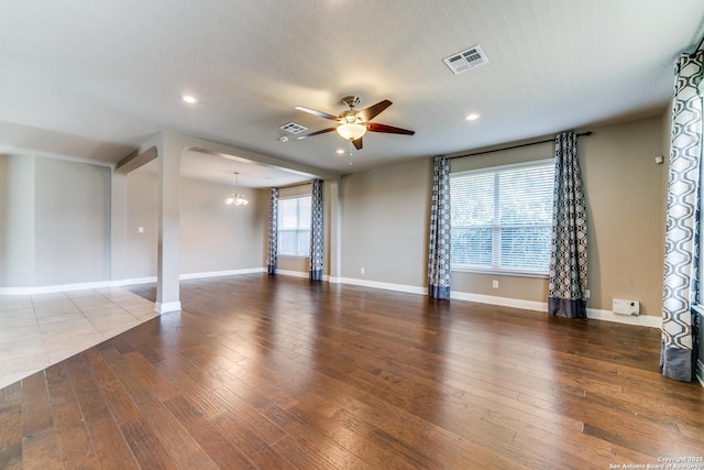 unfurnished room with wood-type flooring, ceiling fan with notable chandelier, and a textured ceiling