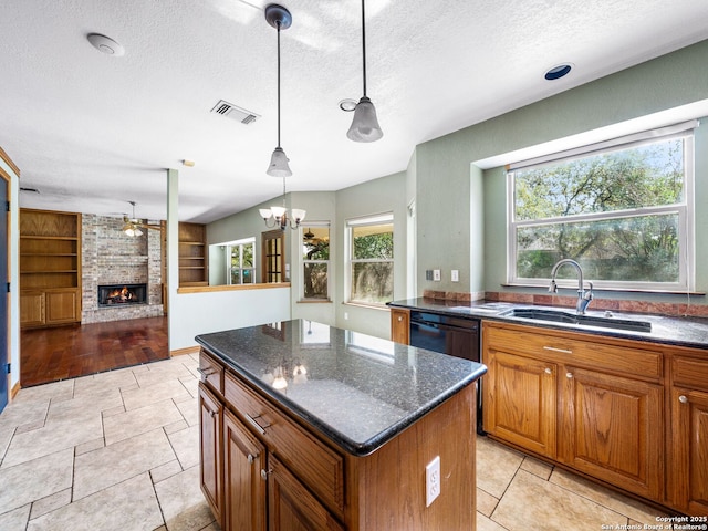 kitchen featuring a kitchen island, pendant lighting, a fireplace, sink, and dark stone countertops