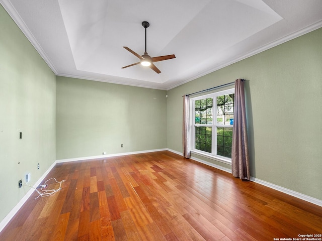 empty room featuring ornamental molding, wood-type flooring, and a tray ceiling