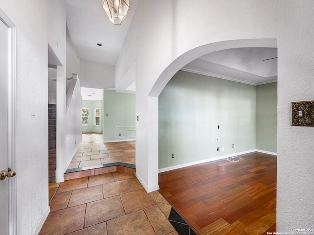 hall with ornamental molding, a towering ceiling, and tile patterned floors