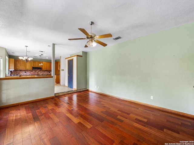 unfurnished living room featuring hardwood / wood-style flooring, sink, ceiling fan with notable chandelier, and a textured ceiling