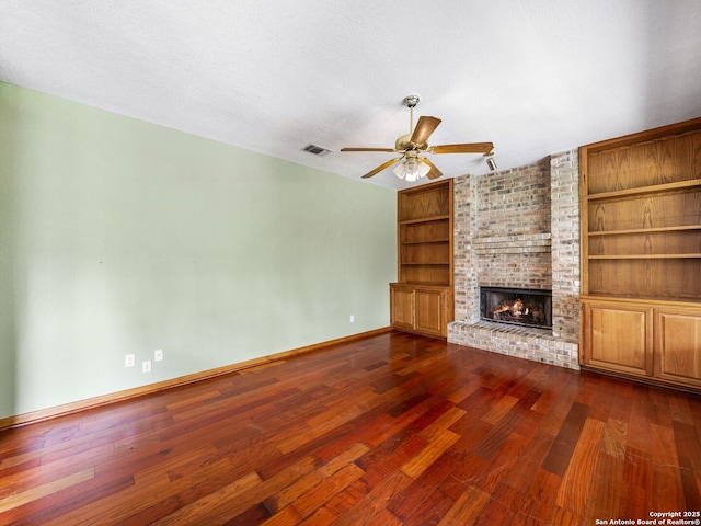 unfurnished living room with a fireplace, dark wood-type flooring, built in features, and a textured ceiling