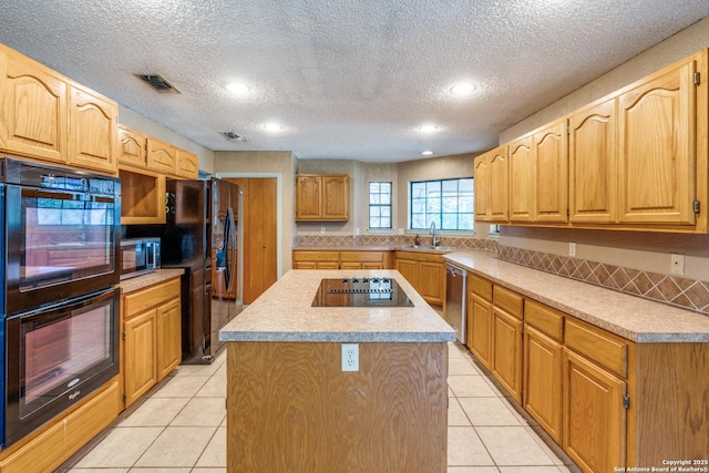 kitchen featuring sink, light tile patterned floors, a kitchen island, and black appliances