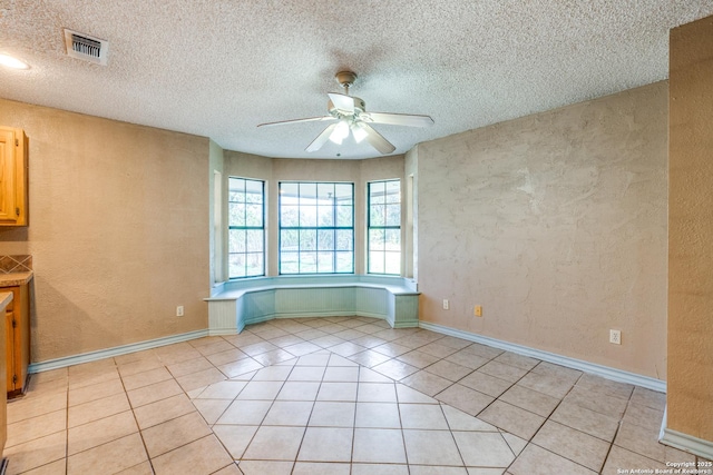 tiled empty room featuring a textured ceiling and ceiling fan