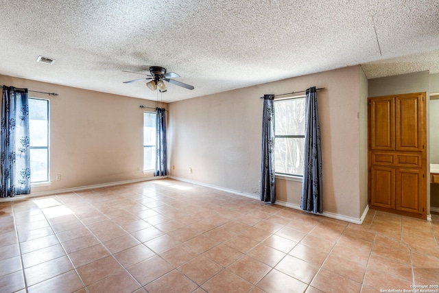 empty room featuring a textured ceiling, ceiling fan, and light tile patterned flooring