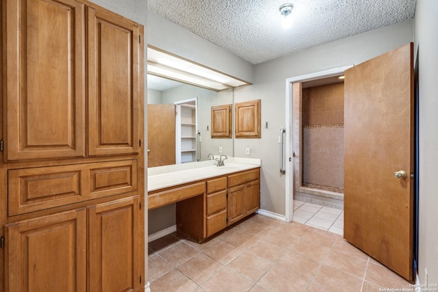 bathroom with tile patterned flooring, vanity, a textured ceiling, and a shower with shower door