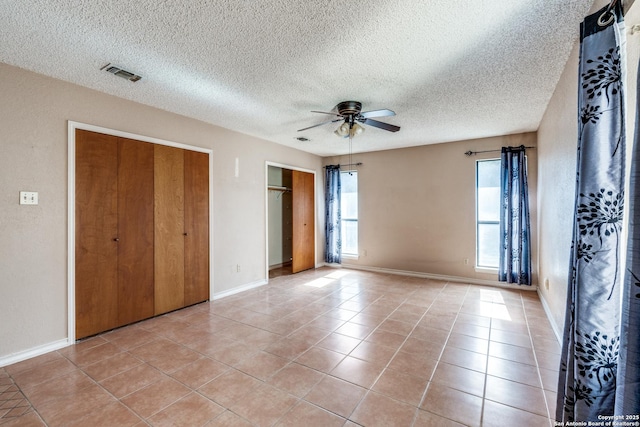 unfurnished bedroom featuring light tile patterned floors, a textured ceiling, and ceiling fan