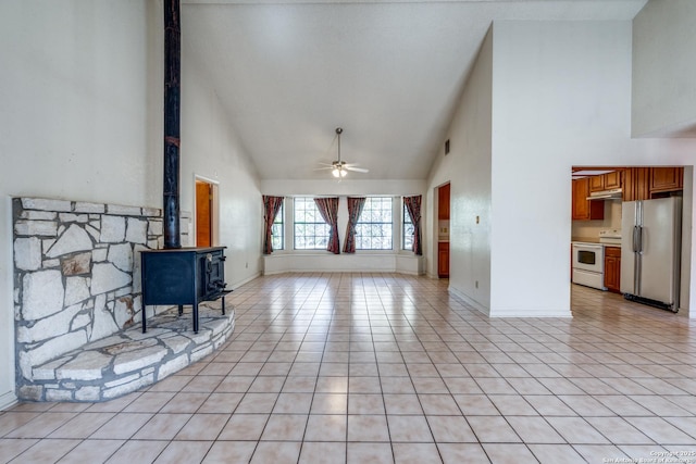 tiled living room featuring high vaulted ceiling, ceiling fan, and a wood stove