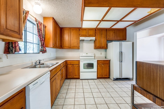 kitchen with white appliances, sink, a textured ceiling, and light tile patterned floors