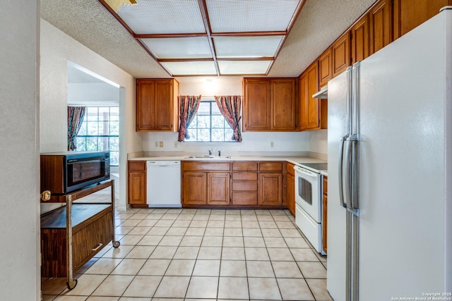 kitchen with sink, white appliances, a textured ceiling, and light tile patterned flooring