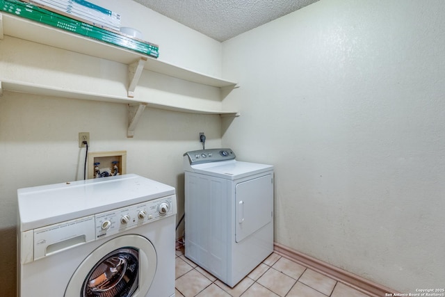 washroom featuring washing machine and clothes dryer, a textured ceiling, and light tile patterned floors