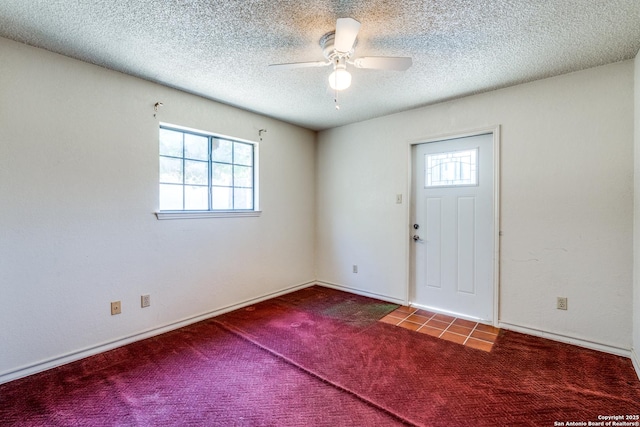 entrance foyer with ceiling fan, a wealth of natural light, a textured ceiling, and carpet flooring