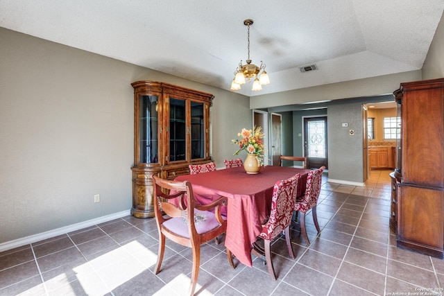 dining space with dark tile patterned floors and an inviting chandelier