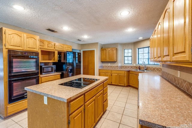 kitchen with sink, light tile patterned floors, a kitchen island, decorative backsplash, and black appliances