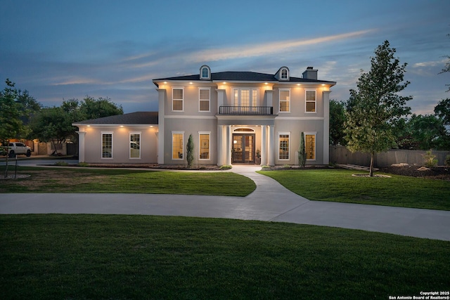 view of front of house with a balcony, french doors, stucco siding, and a chimney