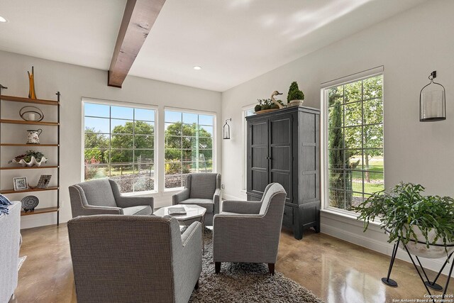 living area featuring baseboards, finished concrete flooring, beamed ceiling, healthy amount of natural light, and recessed lighting