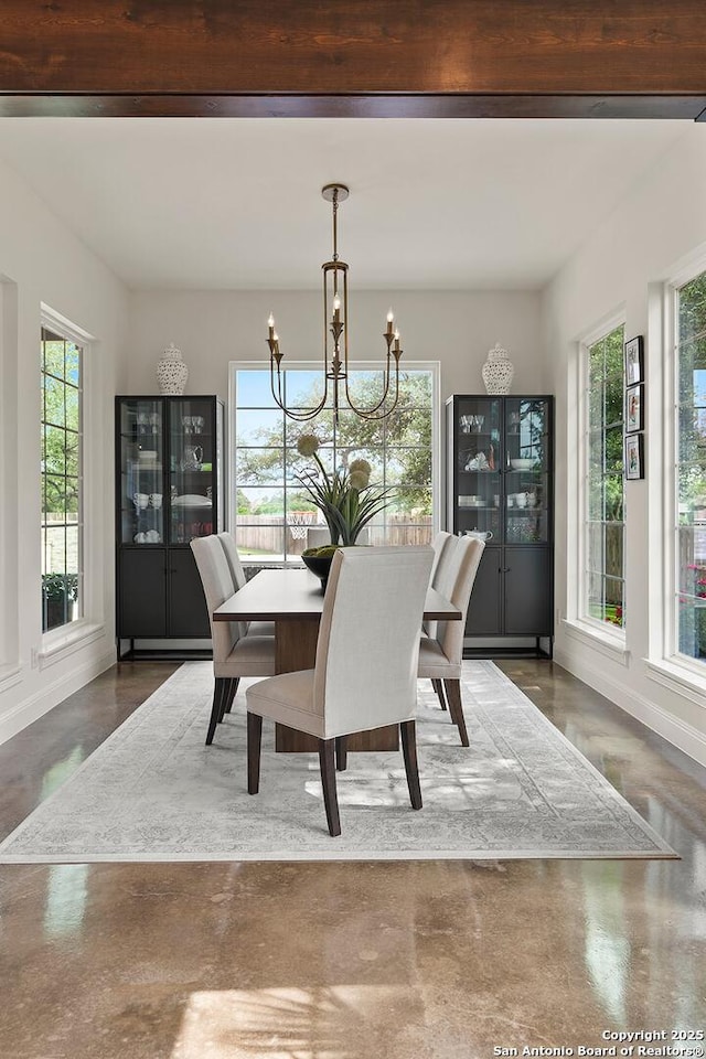 dining room featuring a chandelier, baseboards, and concrete flooring