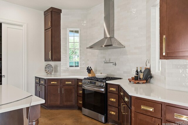 kitchen with gas stove, wall chimney range hood, backsplash, and light countertops