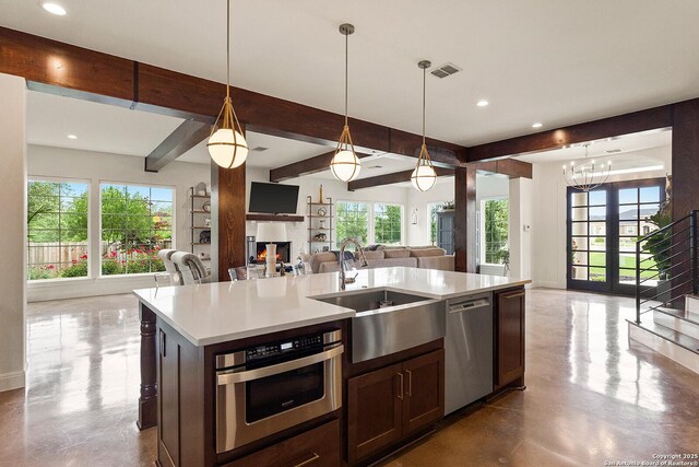 kitchen featuring open floor plan, stainless steel dishwasher, a sink, recessed lighting, and plenty of natural light